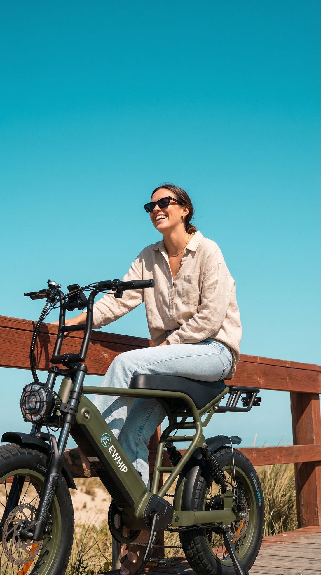 Woman smiling on stylish green e-bike, enjoying sunny day outdoors