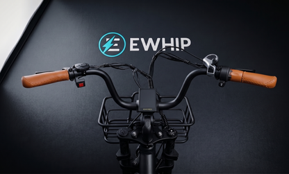 Bicycle handlebar with wooden grips and a basket on a black background with EWHIP logo.