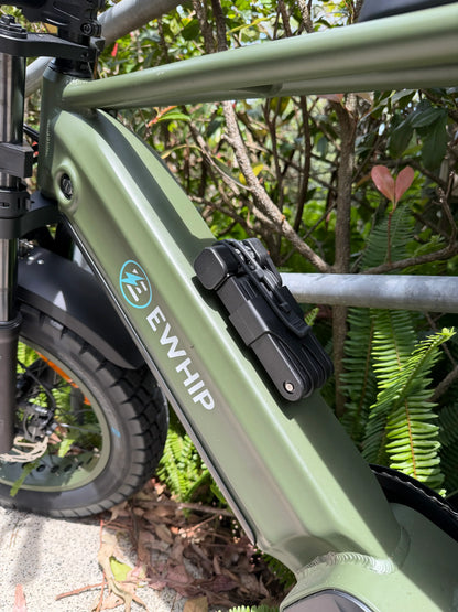 Green EWHIP e-bike with Samsung battery, EN15194 certified, parked outdoors near foliage