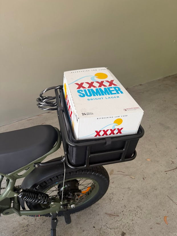 E-bike with rear cargo basket carrying XXXX Summer Lager beer box, showcasing practical storage for daily errands.