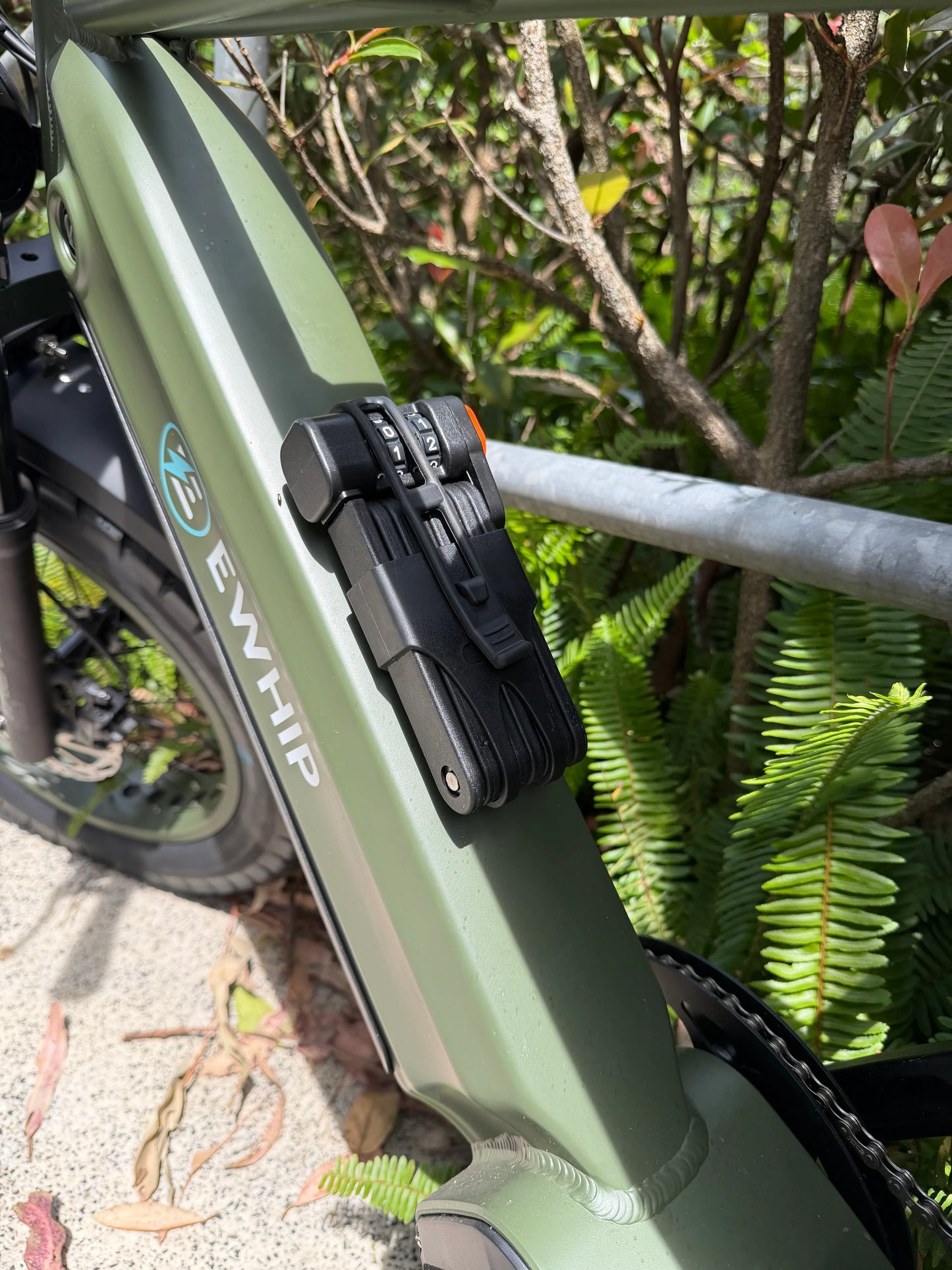 Green EWHIP e-bike with secure lock, surrounded by lush greenery, showcasing stylish street-legal design.