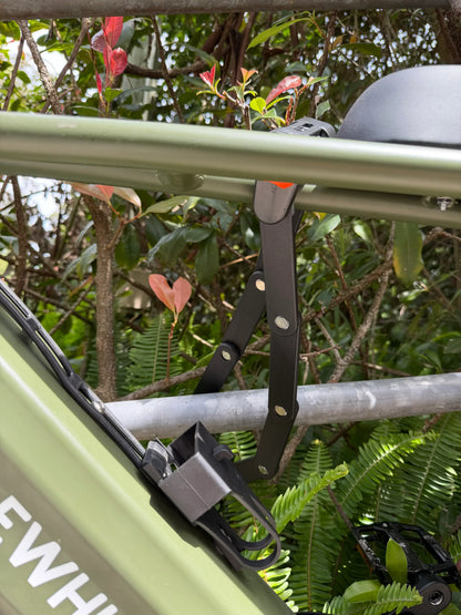 Green e-bike frame with black mounting bracket, surrounded by lush greenery and red leaves.